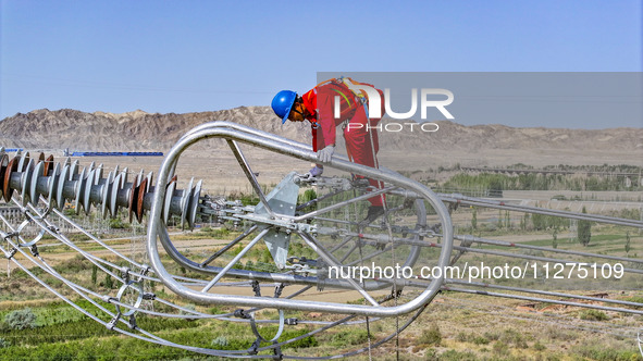 Construction workers are erecting a power grid at a height at the Bazhou-Tieganlik-Ruoqiang 750 kV transmission line project site in Korla,...