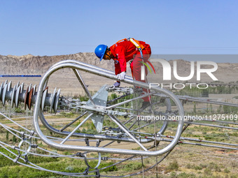 Construction workers are erecting a power grid at a height at the Bazhou-Tieganlik-Ruoqiang 750 kV transmission line project site in Korla,...