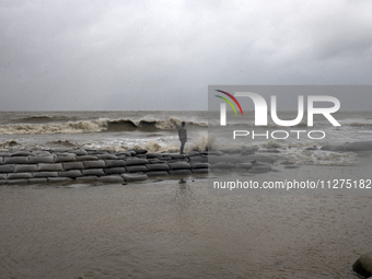 A tourist is walking through Kuakata Sea Beach in southern Bangladesh on May 26, 2024, as Cyclone Remal nears. The Met Office is issuing a g...