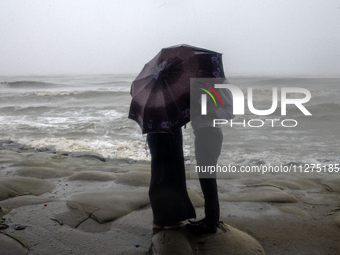 A couple is trying to escape the rain by holding an umbrella at Kuakata Sea Beach in southern Bangladesh on May 26, 2024, as Cyclone Remal n...