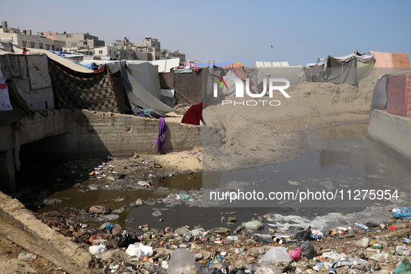 Displaced Palestinians are walking between their tents that they have set up next to the beach, in Deir el-Balah, central Gaza Strip, on May...