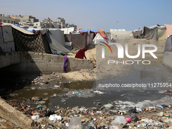 Displaced Palestinians are walking between their tents that they have set up next to the beach, in Deir el-Balah, central Gaza Strip, on May...