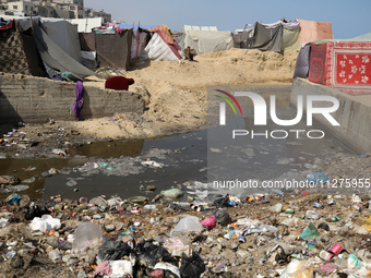 Displaced Palestinians are walking between their tents that they have set up next to the beach, in Deir el-Balah, central Gaza Strip, on May...