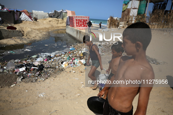 Displaced Palestinians are walking between their tents that they have set up next to the beach, in Deir el-Balah, central Gaza Strip, on May...