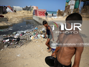 Displaced Palestinians are walking between their tents that they have set up next to the beach, in Deir el-Balah, central Gaza Strip, on May...