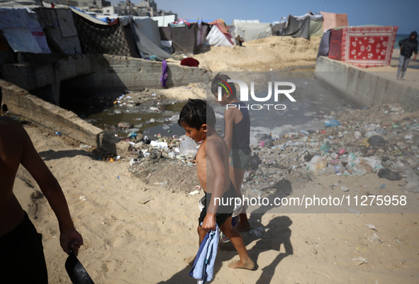 Displaced Palestinians are walking between their tents that they have set up next to the beach, in Deir el-Balah, central Gaza Strip, on May...