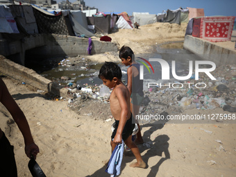 Displaced Palestinians are walking between their tents that they have set up next to the beach, in Deir el-Balah, central Gaza Strip, on May...