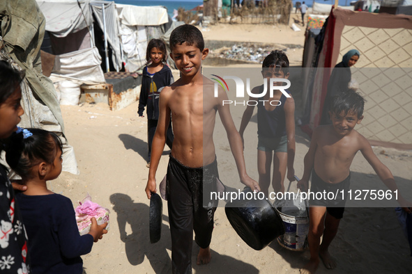 Displaced Palestinians are walking between their tents that they have set up next to the beach, in Deir el-Balah, central Gaza Strip, on May...