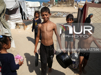 Displaced Palestinians are walking between their tents that they have set up next to the beach, in Deir el-Balah, central Gaza Strip, on May...