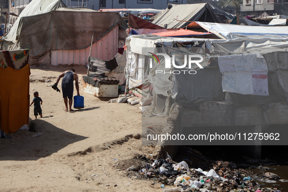 Displaced Palestinians are walking between their tents that they have set up next to the beach, in Deir el-Balah, central Gaza Strip, on May...