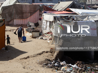 Displaced Palestinians are walking between their tents that they have set up next to the beach, in Deir el-Balah, central Gaza Strip, on May...