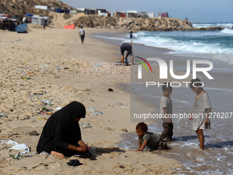 Displaced Palestinians are walking between their tents that they are setting up next to the beach, in Deir el-Balah, central Gaza Strip, on...