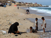 Displaced Palestinians are walking between their tents that they are setting up next to the beach, in Deir el-Balah, central Gaza Strip, on...