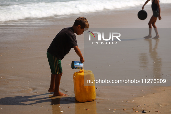 A Palestinian boy is washing kitchenware on the beach in Deir el-Balah, central Gaza Strip, on May 26, 2024, amid the ongoing conflict betwe...