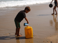 A Palestinian boy is washing kitchenware on the beach in Deir el-Balah, central Gaza Strip, on May 26, 2024, amid the ongoing conflict betwe...