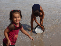 A Palestinian boy is washing kitchenware on the beach in Deir el-Balah, central Gaza Strip, on May 26, 2024, amid the ongoing conflict betwe...