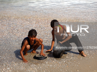 A Palestinian boy is washing kitchenware on the beach in Deir el-Balah, central Gaza Strip, on May 26, 2024, amid the ongoing conflict betwe...