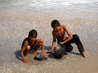 A Palestinian boy is washing kitchenware on the beach in Deir el-Balah, central Gaza Strip, on May 26, 2024, amid the ongoing conflict betwe...