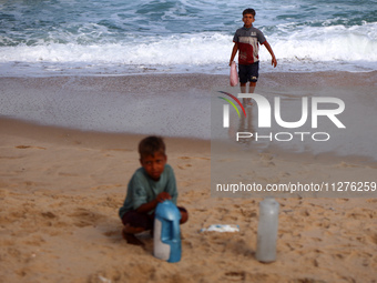 Displaced Palestinians are walking between their tents that they are setting up next to the beach, in Deir el-Balah, central Gaza Strip, on...