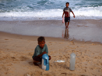 Displaced Palestinians are walking between their tents that they are setting up next to the beach, in Deir el-Balah, central Gaza Strip, on...