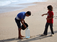 Displaced Palestinians are walking between their tents that they are setting up next to the beach, in Deir el-Balah, central Gaza Strip, on...