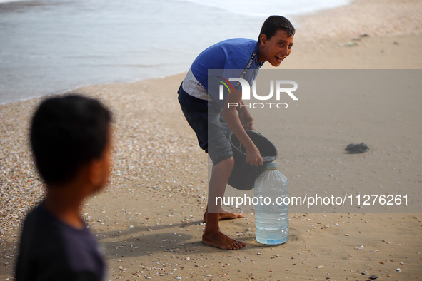 Displaced Palestinians are walking between their tents that they are setting up next to the beach, in Deir el-Balah, central Gaza Strip, on...