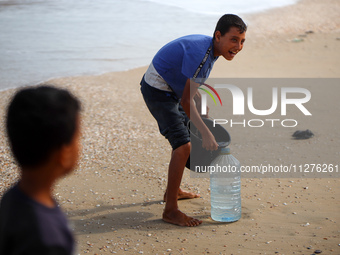 Displaced Palestinians are walking between their tents that they are setting up next to the beach, in Deir el-Balah, central Gaza Strip, on...