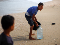 Displaced Palestinians are walking between their tents that they are setting up next to the beach, in Deir el-Balah, central Gaza Strip, on...