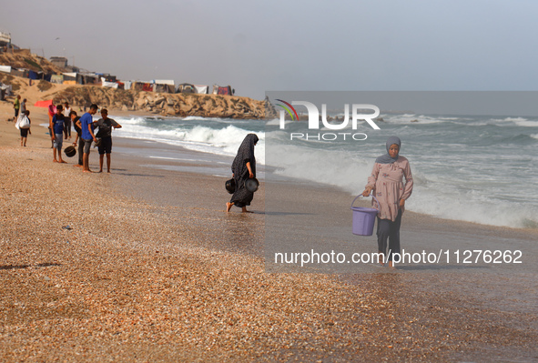 A Palestinian is collecting sea water to wash clothes at the beach in Deir el-Balah, central Gaza Strip, on May 26, 2024, amid the ongoing c...