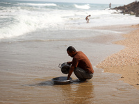 A Palestinian man is washing kitchenware on the beach in Deir el-Balah, central Gaza Strip, on May 26, 2024, amid the ongoing conflict betwe...