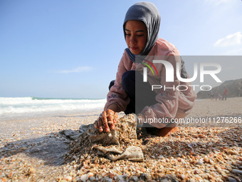 A Palestinian woman is washing clothes at the beach in Deir el-Balah, central Gaza Strip, on May 26, 2024, amid the ongoing conflict between...