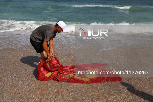 A Palestinian is collecting sea water to wash clothes at the beach in Deir el-Balah, central Gaza Strip, on May 26, 2024, amid the ongoing c...