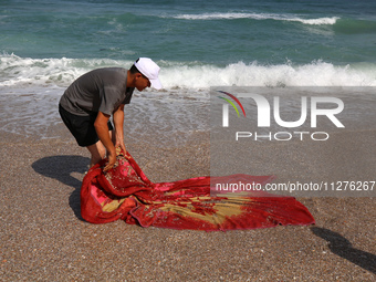 A Palestinian is collecting sea water to wash clothes at the beach in Deir el-Balah, central Gaza Strip, on May 26, 2024, amid the ongoing c...