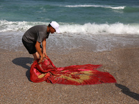 A Palestinian is collecting sea water to wash clothes at the beach in Deir el-Balah, central Gaza Strip, on May 26, 2024, amid the ongoing c...