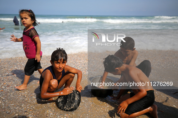 A Palestinian is collecting sea water to wash clothes at the beach in Deir el-Balah, central Gaza Strip, on May 26, 2024, amid the ongoing c...