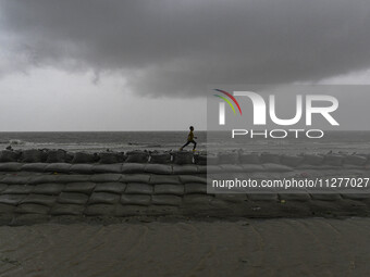 A boy is playing on an embankment in Kuakata, Bangladesh, on May 26, 2024, ahead of cyclone Remal's landfall in Bangladesh. (