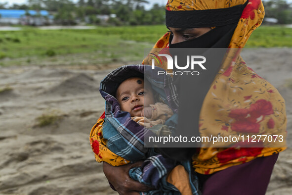 A woman is carrying a child as she is walking towards a shelter during a rainfall in Kuakata, Bangladesh, on May 26, 2024, ahead of cyclone...