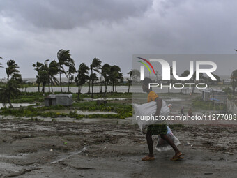 A man is walking with his belongings towards a shelter during a rainfall in Kuakata, Bangladesh, on May 26, 2024, ahead of cyclone Remal's l...