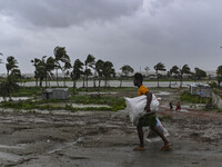 A man is walking with his belongings towards a shelter during a rainfall in Kuakata, Bangladesh, on May 26, 2024, ahead of cyclone Remal's l...