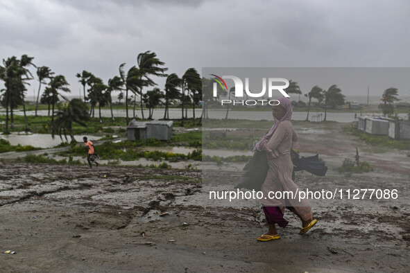 A woman is walking with her belongings towards a shelter during a rainfall in Kuakata, Bangladesh, on May 26, 2024, ahead of cyclone Remal's...