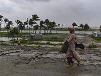 A woman is walking with her belongings towards a shelter during a rainfall in Kuakata, Bangladesh, on May 26, 2024, ahead of cyclone Remal's...