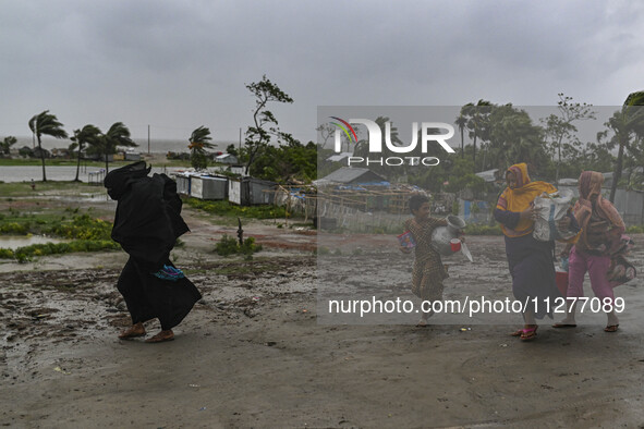 A Bangladeshi woman is walking with her belongings towards a shelter during a rainfall in Kuakata, Bangladesh, on May 26, 2024, ahead of cyc...