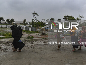 A Bangladeshi woman is walking with her belongings towards a shelter during a rainfall in Kuakata, Bangladesh, on May 26, 2024, ahead of cyc...