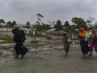 A Bangladeshi woman is walking with her belongings towards a shelter during a rainfall in Kuakata, Bangladesh, on May 26, 2024, ahead of cyc...