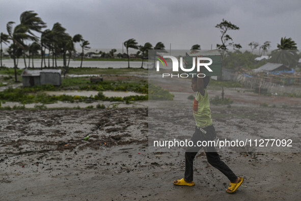 A boy is walking with his belongings towards a shelter during a rainfall in Kuakata, Bangladesh, on May 26, 2024, ahead of cyclone Remal's l...