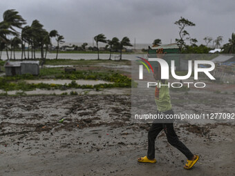 A boy is walking with his belongings towards a shelter during a rainfall in Kuakata, Bangladesh, on May 26, 2024, ahead of cyclone Remal's l...