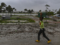 A boy is walking with his belongings towards a shelter during a rainfall in Kuakata, Bangladesh, on May 26, 2024, ahead of cyclone Remal's l...