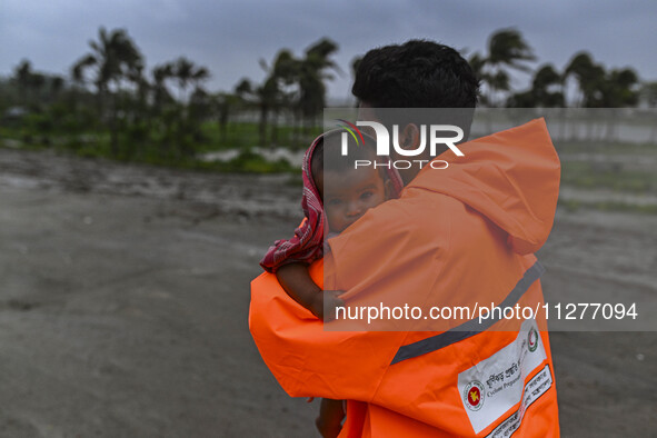 A volunteer is carrying a baby girl to take shelter in the Cyclone Shelter in Kuakata, Bangladesh, on May 26, 2024, ahead of cyclone Remal's...