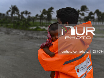 A volunteer is carrying a baby girl to take shelter in the Cyclone Shelter in Kuakata, Bangladesh, on May 26, 2024, ahead of cyclone Remal's...