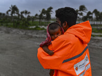 A volunteer is carrying a baby girl to take shelter in the Cyclone Shelter in Kuakata, Bangladesh, on May 26, 2024, ahead of cyclone Remal's...